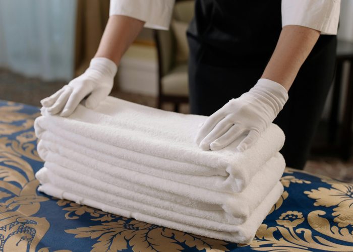 pexels-photo-6466227-6466227 Professional housekeeper folding clean towels on a bed in a hotel room, emphasizing neatness and service.